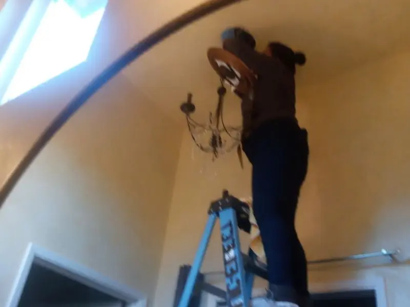 Electrician installing a chandelier in a Portville residence